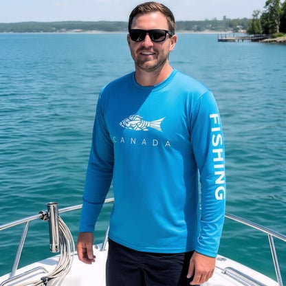 A man wearing sunglasses and a bright blue long-sleeve performance fishing shirt standing on a boat, featuring a white fish graphic with "CANADA" on the front and "FISHING" printed down the sleeve.