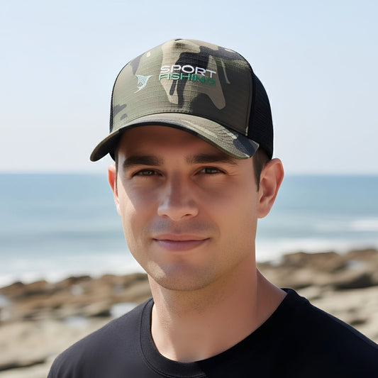 A man wearing a camouflage trucker hat with the Norte sport fishing logo, standing on a beach with the ocean and rocks in the background.