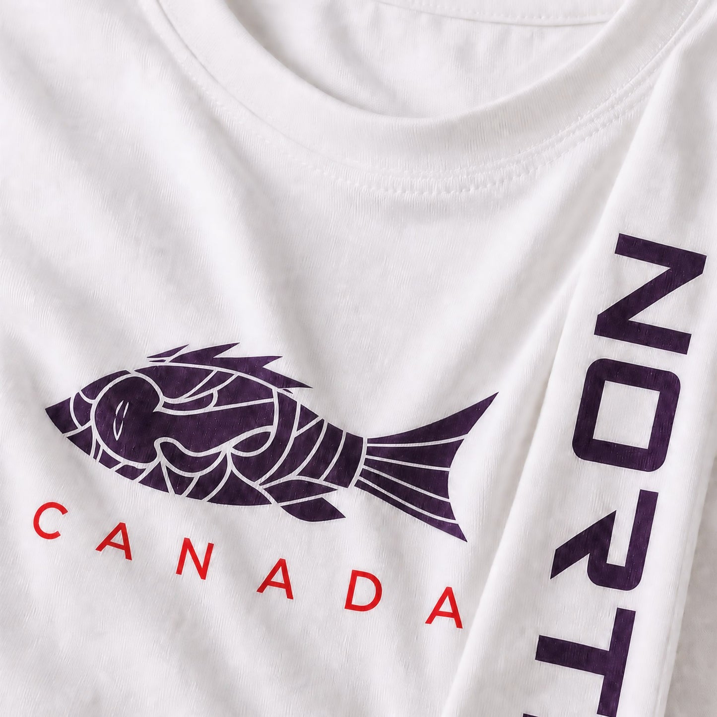 Close up detail of kids youth white long sleeve shirt showing dark black fish graphic, red CANADA text, and vertical NORTE sleeve branding