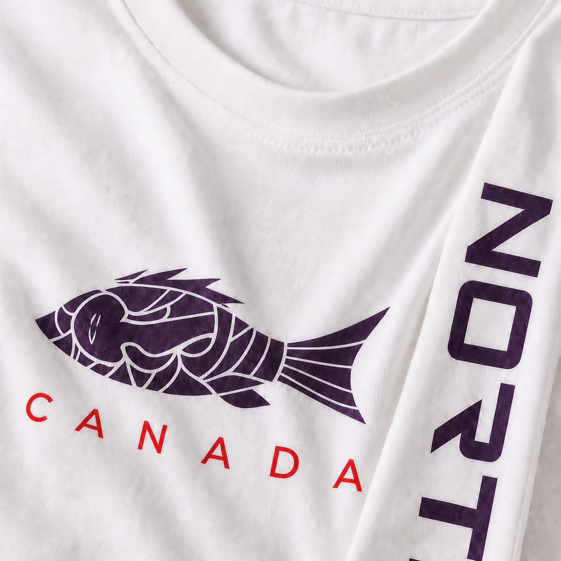 Close up detail of kids youth white long sleeve shirt showing dark black fish graphic, red CANADA text, and vertical NORTE sleeve branding