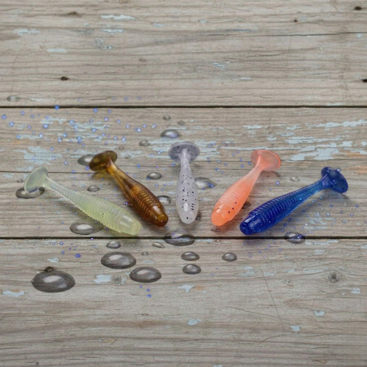 Norte 1.77 inch paddle tail finesse fishing lures in five colors on a wet wooden dock background