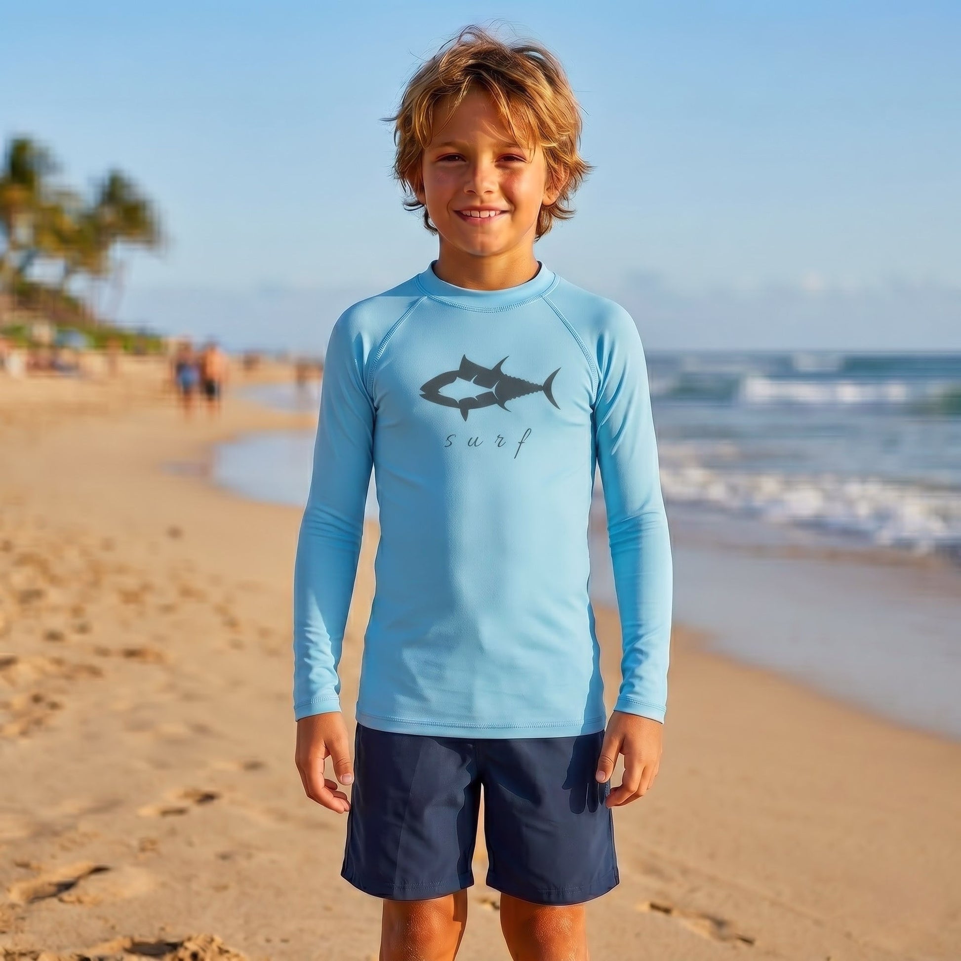 Youth long sleeve performance rash guard in Sky Blue with tuna fish graphic and surf script, featuring UPF sun protection and moisture-wicking fabric for kids fishing and beach days.